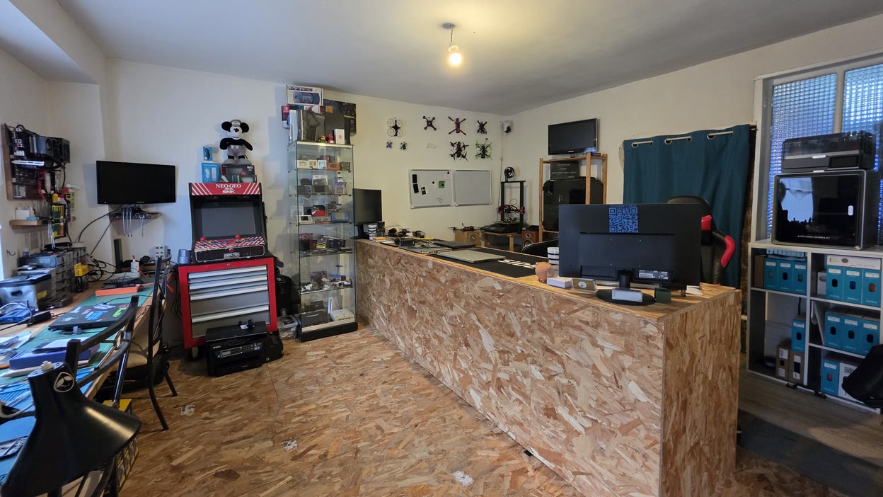 Vue d'ensemble de l'atelier : l'établi et son mur d'outillage, la vitrine d'appareils et le comptoir — l'atelier Docteur High Tech, à Lubersac