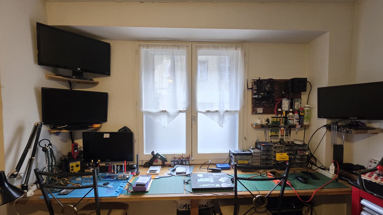 L'établi vu de près : le mur d'outillage, les tiroirs de pièces et le plan de travail, sous la lumière de la fenêtre — l'atelier Docteur High Tech, à Lubersac